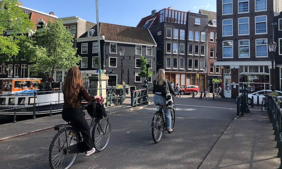 Two women cycling over a bridge in Amsterdam